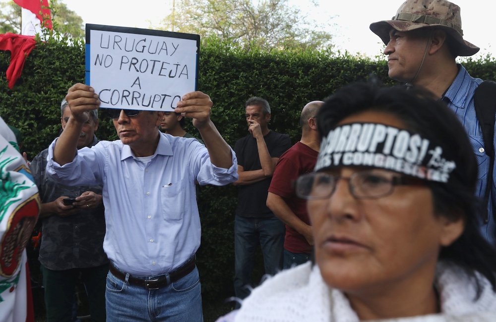 A man opposed to former Peruvian President Alan Garcia holds a sign Nov. 18 reading "Uruguay