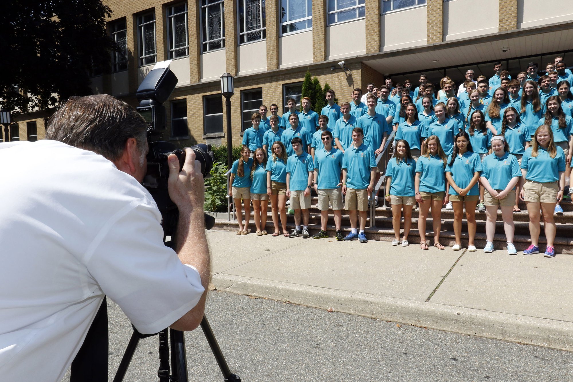 Marianist Brother Roger Poletti snaps a group photo following a commissioning Mass for World Youth Day pilgrims July 17 at Kellenberg Memorial High School in Uniondale