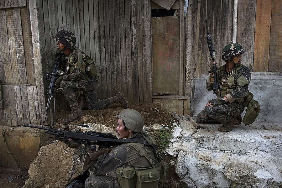 Soldiers take positions while evading sniper fire as they try to clear Marawi of armed militants one street at a time