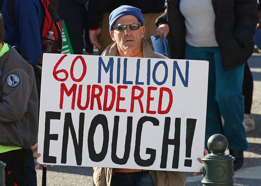 A pro-life advocate holds a sign while walking up Constitution Avenue en route to the U.S. Supreme Court during the 45th annual March for Life in Washington Jan. 19. (CNS photo/Gregory A. Shemitz)