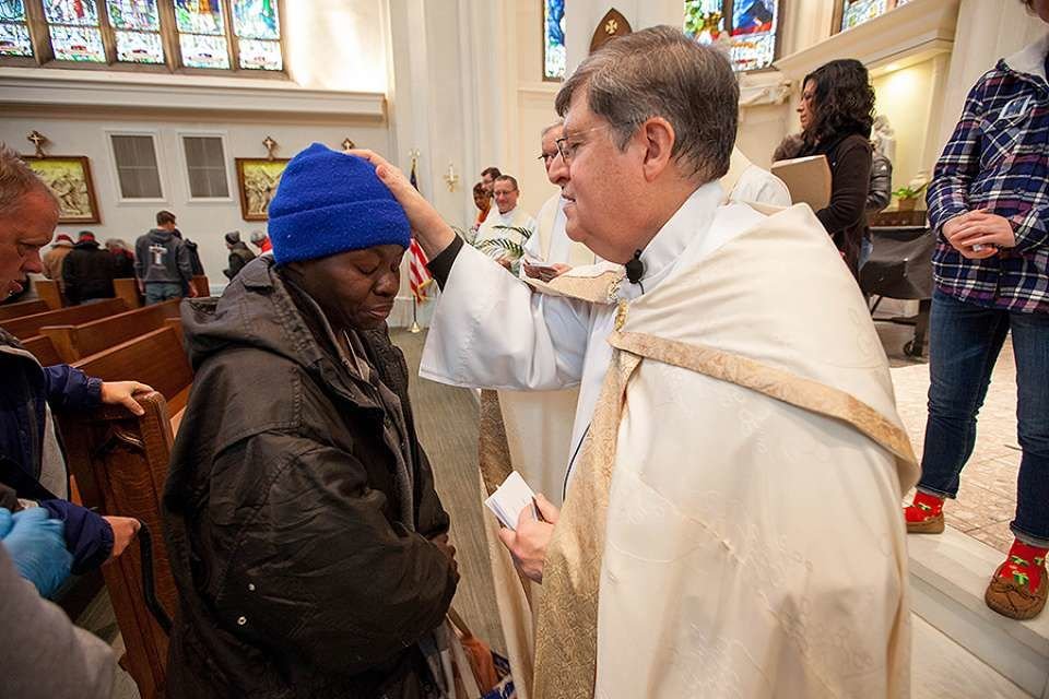 Fr. Cattany blesses an attendee of the annual Father Woody Christmas cash giveaway