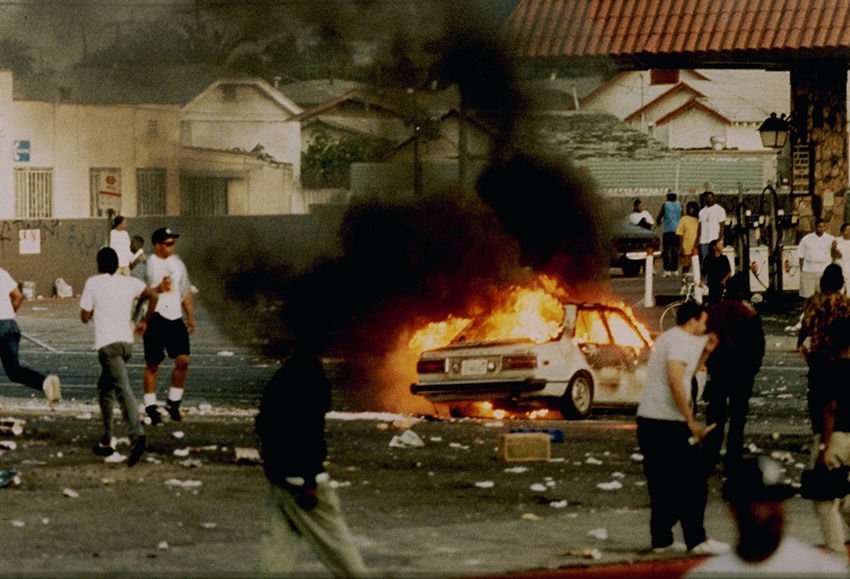 A car burns as looters take to the streets at the intersection of Florence and Normandie Avenues