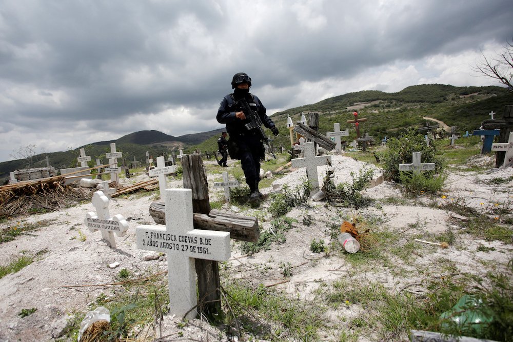 A federal policeman keeps watch at a cemetery as relatives of missing persons look for mass graves in Ahuihuiyuco