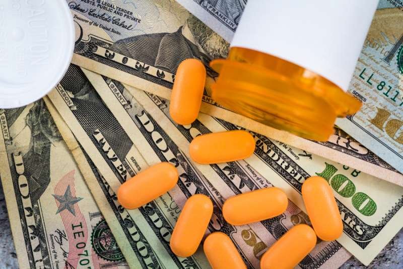 Prescription medicine on dollar bills. Via Shutterstock