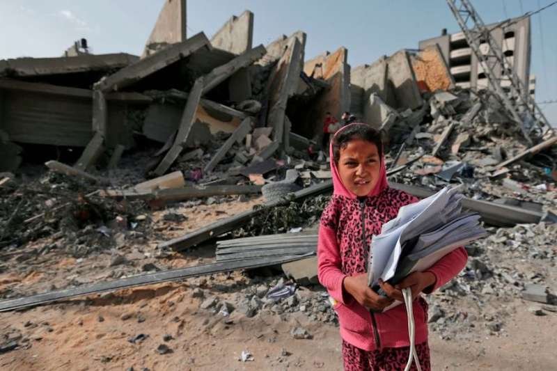 A Palestinian girl stands in front of a building destroyed during Israeli airstrikes in Gaza City. May 6
