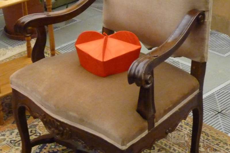 A cardinal's biretta rests on an empty chair. Credit:Alan Holdren/CNA.
