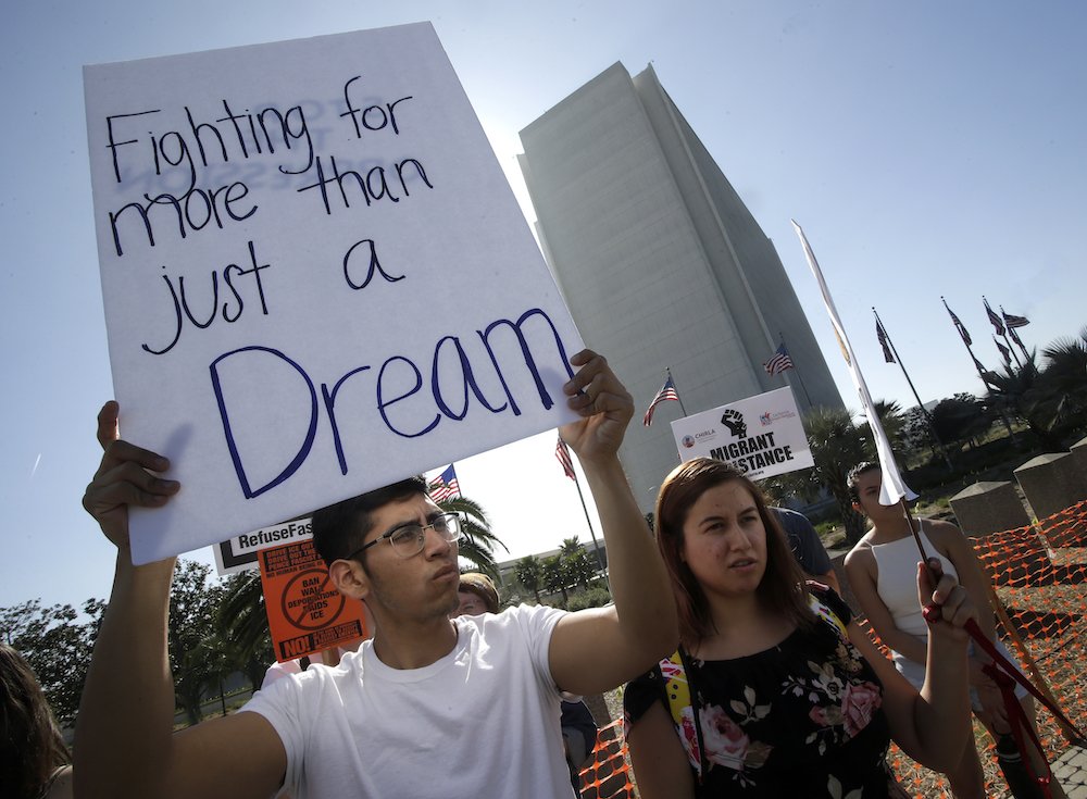 A protester holds a sign that reads "Fighting for more than just a Dream
