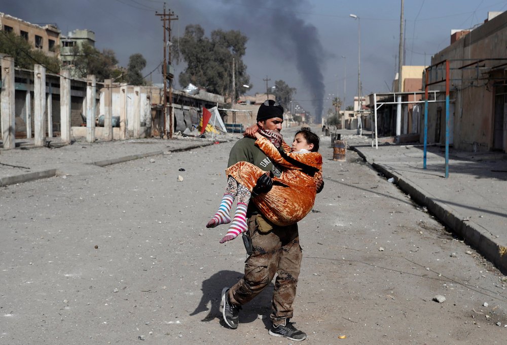 An Iraqi soldier carries an injured woman during a battle with the Islamic State group in Mosul Feb. 28