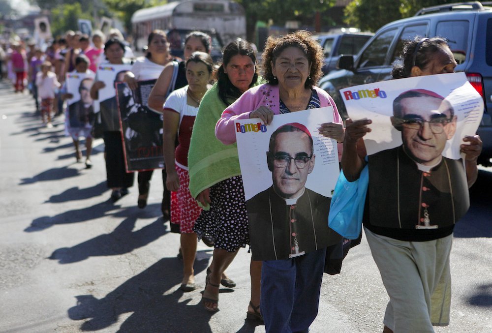 People hold posters showing the image of St. Oscar Romero during a 2014 protest in San Salvador