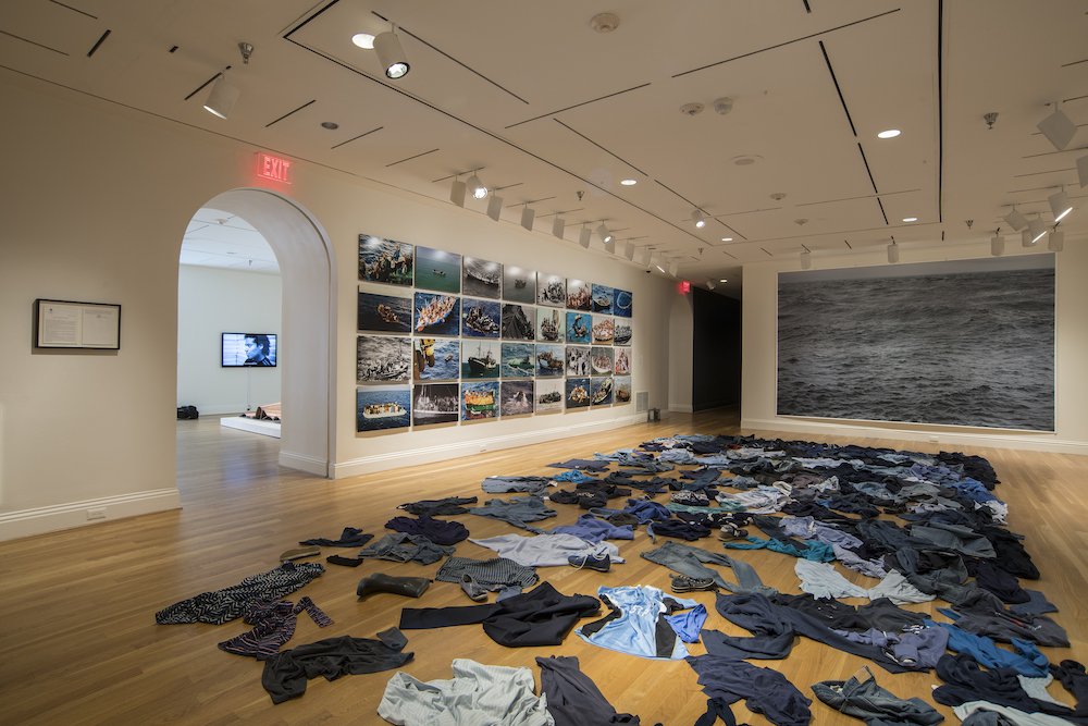 A collection of pants and shirts on the floor at The Phillips Collection museum in Washington illustrates the lives of migrants lost at sea. "The Warmth of other Suns: Stories of Global Displacement" exhibit
