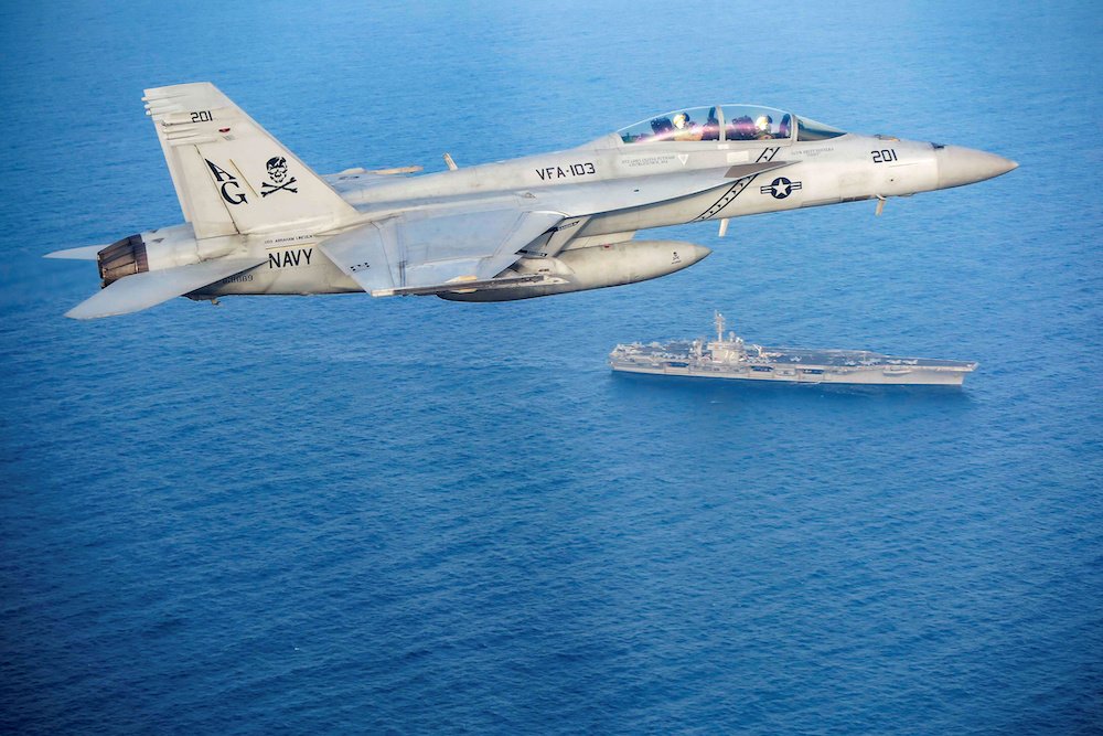 An F/A-18E Super Hornet flies above the aircraft carrier USS Abraham Lincoln in the Arabian Sea May 18