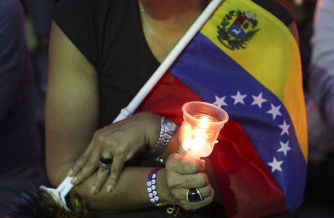 An opponent to Venezuela's President Nicolas Maduro holds a candle during a vigil for those killed in street fighting over the past week in Caracas