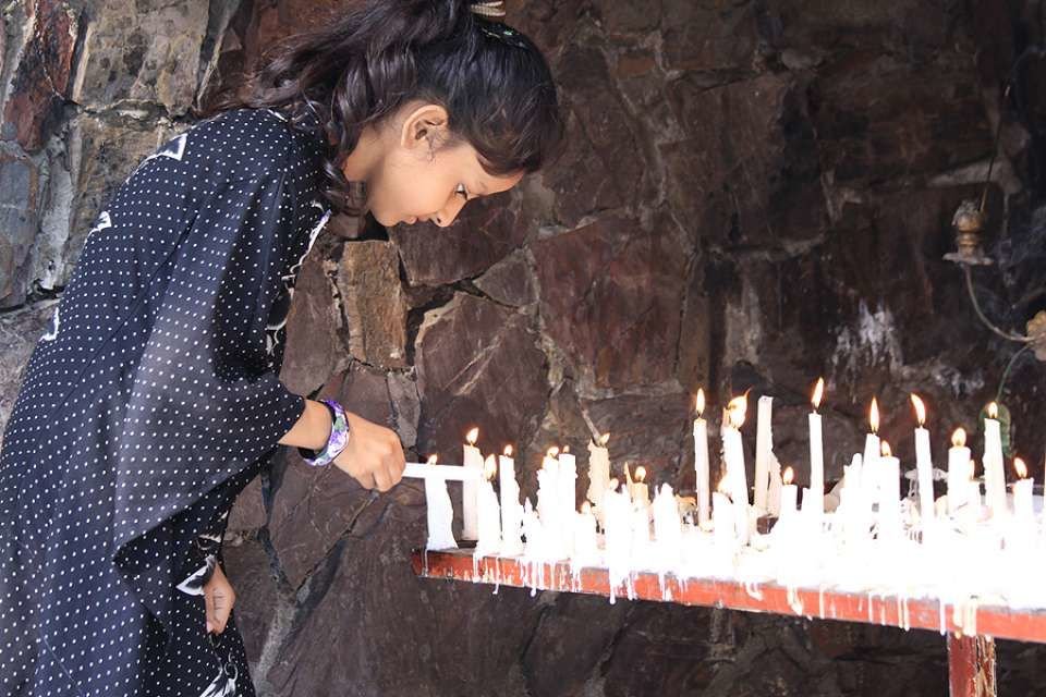 A young girl lights a candle at a Marian Grotto in Pakistan. Credit: Magdalena Wolnik.