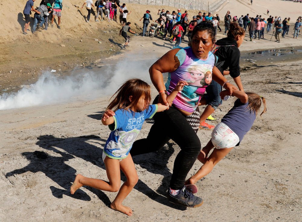 A Honduran migrant family who are part of a caravan trying to reach the U.S. run from tear gas released by U.S. border patrol near Nov. 25 the fence between Mexico and the United States in Tijuana