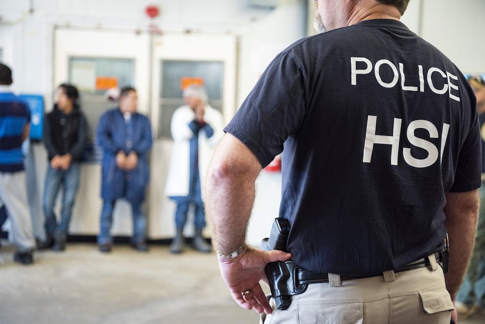 A U.S. Immigration and Customs Enforcement officer looks on after executing search warrants and making arrests Aug. 7