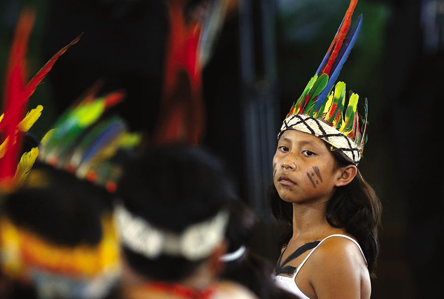 A young member of an indigenous group from the Amazon region listens during a meeting with Pope Francis during a Jan. 19 meeting at Madre de Dios stadium in Puerto Maldonado