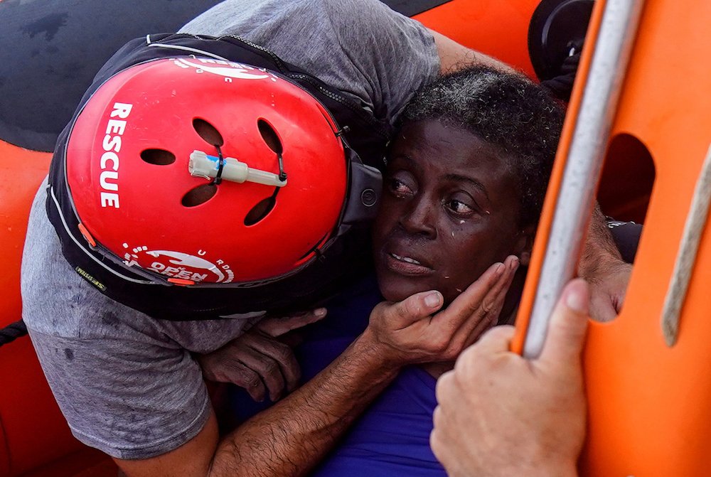 A crew member of the Spanish nongovernmental organization Proactiva Open Arms comforts a rescued African migrant July 17 in central Mediterranean Sea. The main mission of the NGO is sea rescues of refugees that arrive in Europe fleeing wars