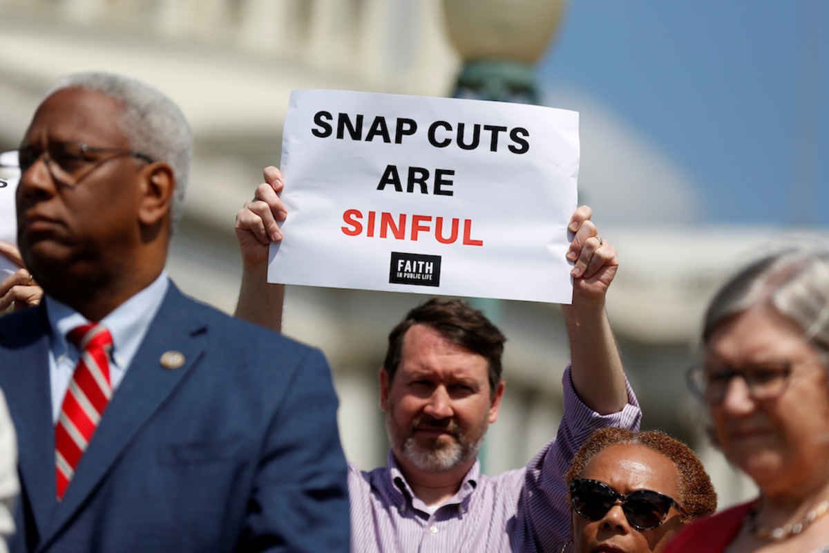 A man holds a sign protesting cuts to the federal Supplemental Nutrition Assistance Program during a news conference on Capitol Hill in Washington May 7