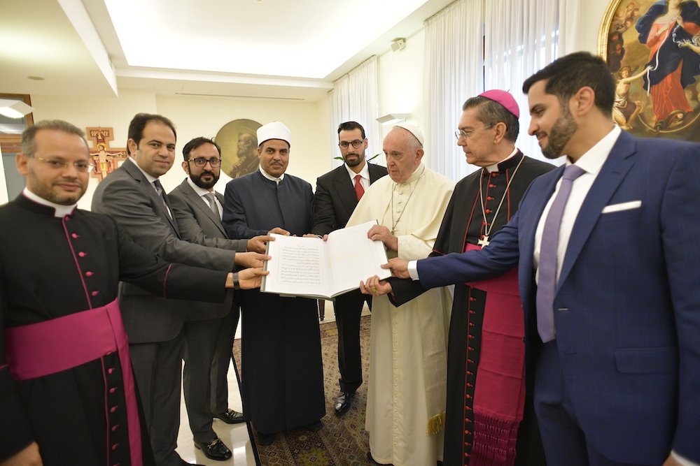 Pope Francis and members of the committee working to fulfill the goals of the "Document on Human Fraternity for World Peace and Living Together" hold a special copy of the document issued by the Vatican Library Sept. 11
