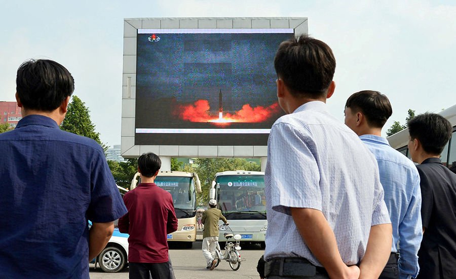 North Koreans watch a news report of an intermediate-range ballistic missile launch on a big screen at Pyongyang station in Pyongyang