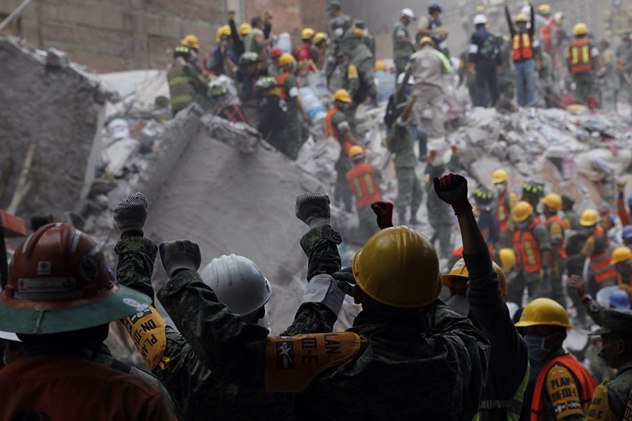Rescue workers hold their hands up for silence to listen for potential victims in the debris of collapsed buildings Sept. 20 following an earthquake in Mexico City. The magnitude 7.1 earthquake hit Sept. 19 to the southeast of the city