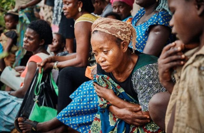 Cameroonian refugees and Nigerians wait for consultations outside a health post April 13