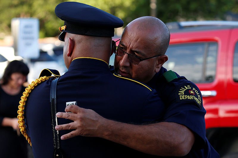 Police officers hug outside Mary Immaculate Catholic Church in Farmers Branch