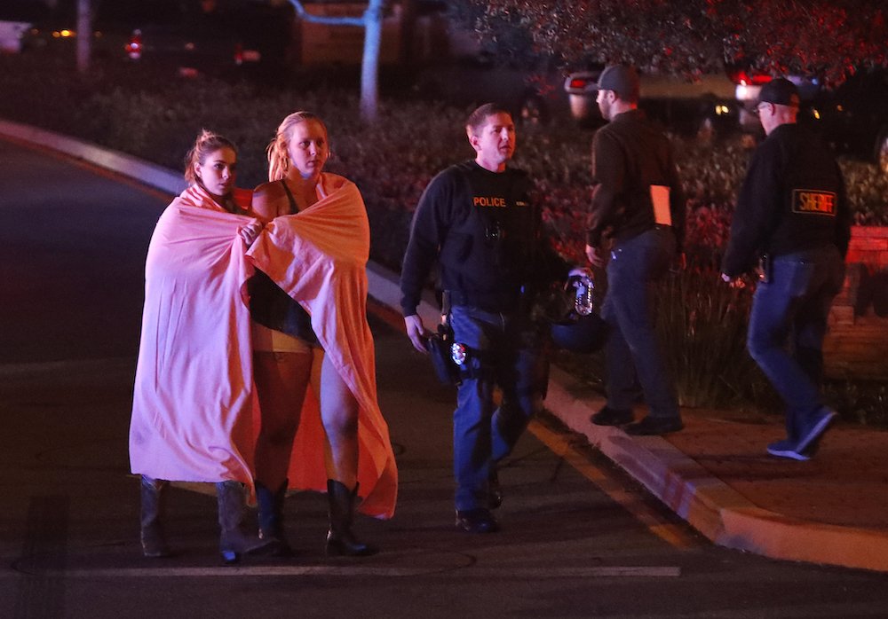 Two women draped in blankets leave the area near the Borderline Bar and Grill in Thousand Oaks