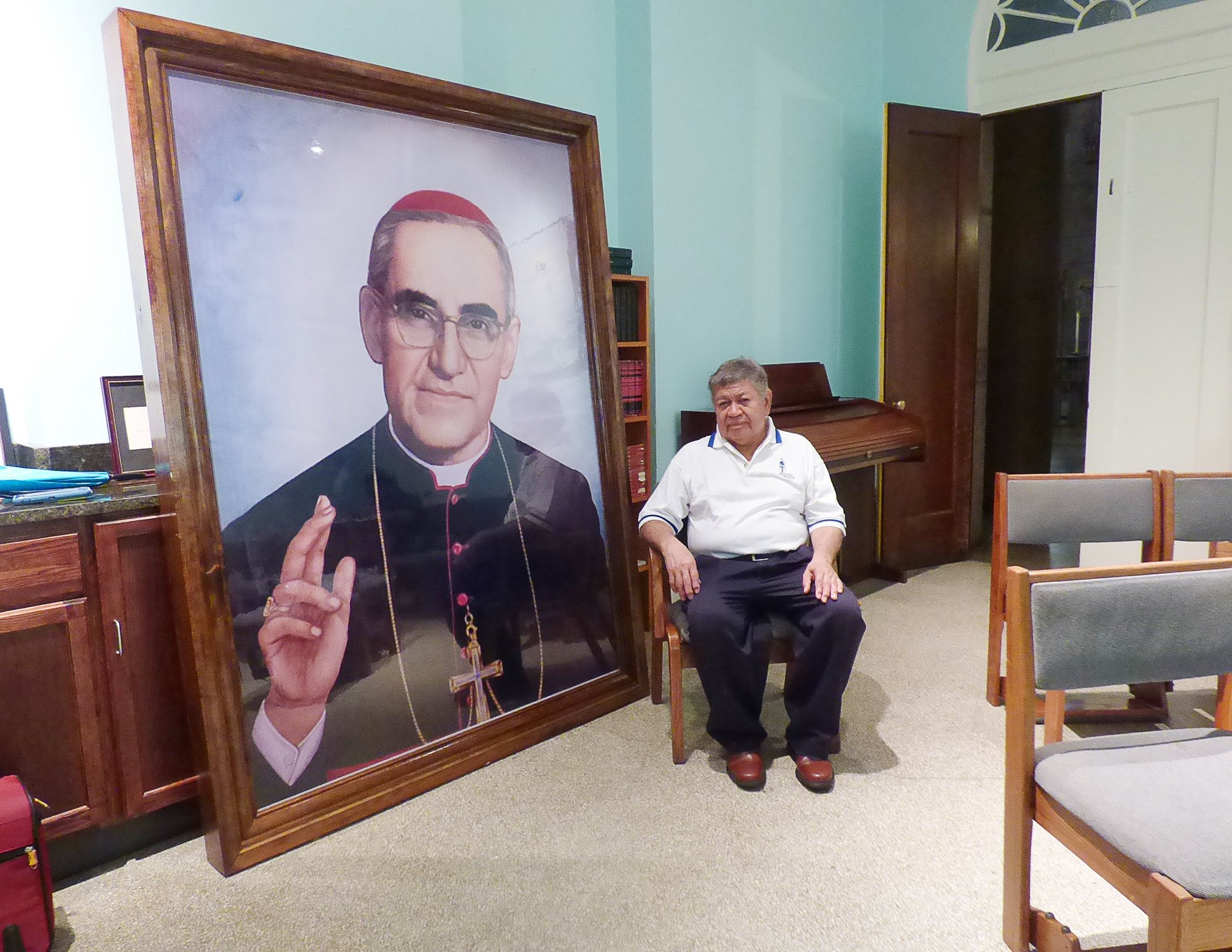Marcelo Perdomo poses in front of large portrait of Blessed Oscar Romero Aug. 2 at the Shrine of the Sacred Heart in Washington. Perdomo worked as a sacristan for Blessed Romero in his native San Miguel