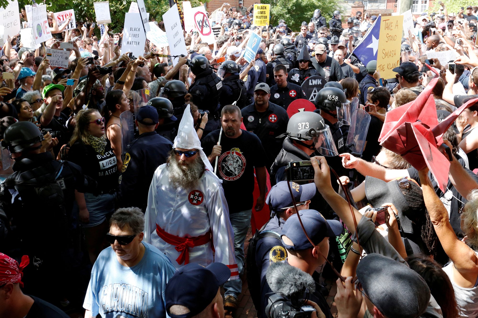 Riot police protect members of the Ku Klux Klan from counter-protesters as they arrive in Charlottesville