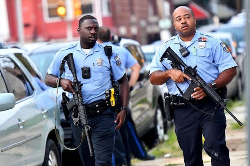 Police officers carrying assault rifles respond to a shooting on August 14