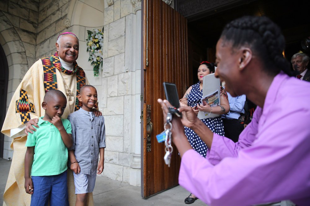 Washington Archbishop Wilton D. Gregory poses with two boys after celebrating Mass at St. Augustine Church in Washington June 2
