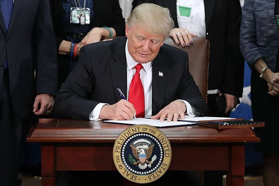 U.S. President Donald Trump signs two executive orders during a visit to the Department of Homeland Security. Credit: hip Somodevilla