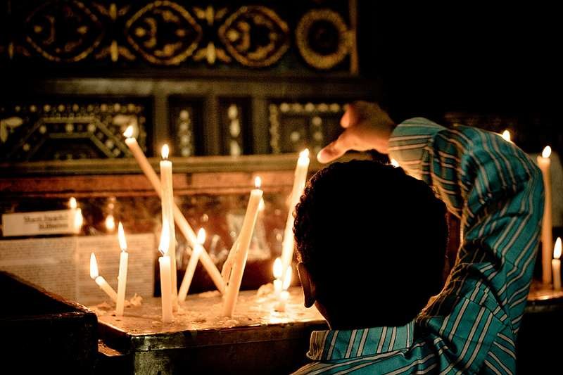A Coptic child lights a candle at a church in Cairo. Credit: Christopher Rose via Flickr (CC BY-NC 2.0).