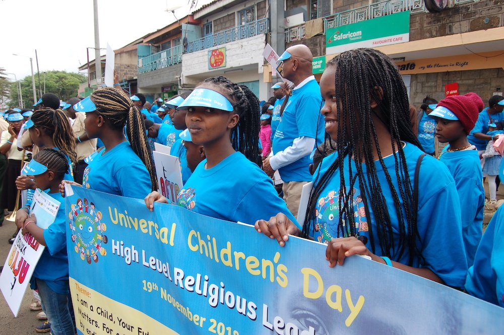 Young women carry a banner as they mark Universal Children's Day in Nairobi