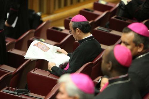 A Bishop reads a newspaper in the Vatican's Synod Hall before the Friday session of the Synod on the Family