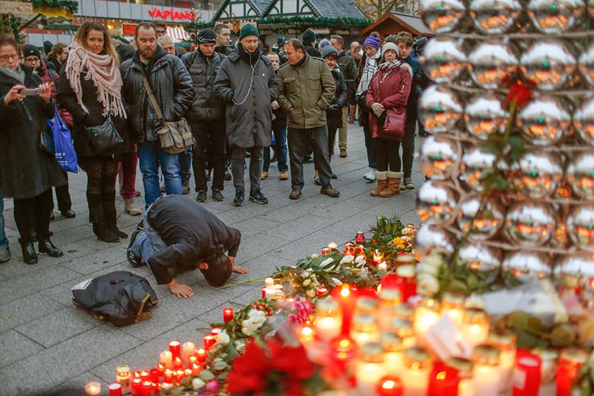 A mourner prays in front of a makeshift memorial Dec. 20 at the scene where a truck plowed into a crowded Christmas market the previous day in Berlin. The terrorist attack killed at least a dozen people and injured nearly 50 as it smashed through tables and wooden stands. (CNS photo/Hannibal Hanschke