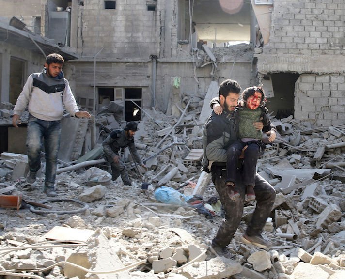 A man carries an injured boy amid destroyed buildings Feb. 21 in rebel-held Eastern Ghouta