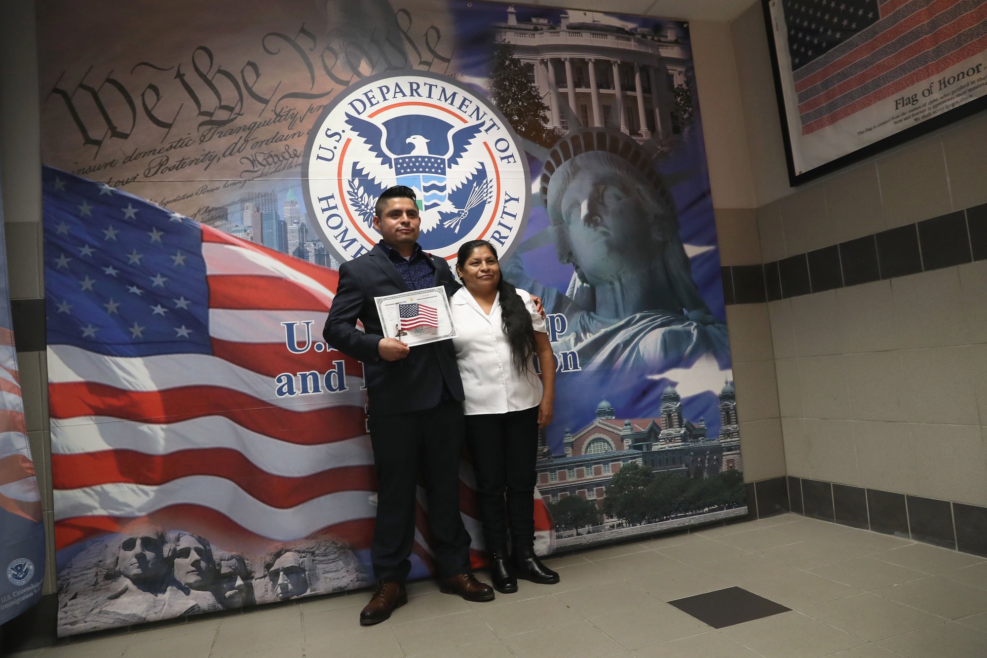 A Mexican immigrant poses for photos with his mother while holding a U.S. citizenship certificate at a naturalization ceremony in New York City.Credit: PHOTO BY JOHN MOORE/GETTY IMAGES 