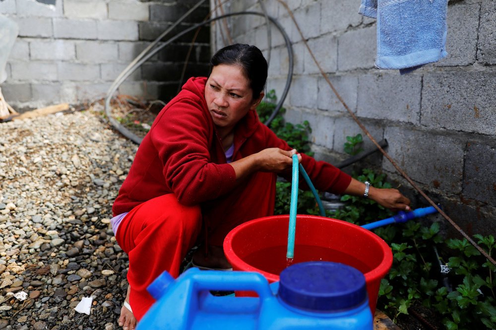 A woman fills containers with water at the only water source near the school-turned-evacuation center in Marawi City