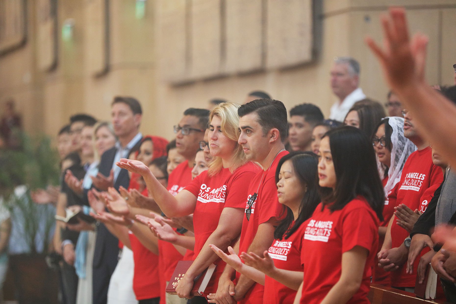 Hundreds of youth and young adults extend their hands to receive a blessing days before departing for Krakow