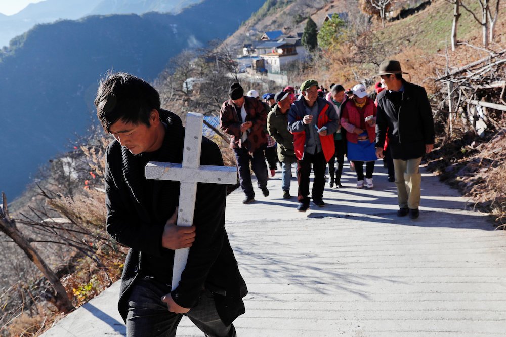 A Tibetan Catholic carries a cross as he walks in a procession on Christmas Eve in Diqing
