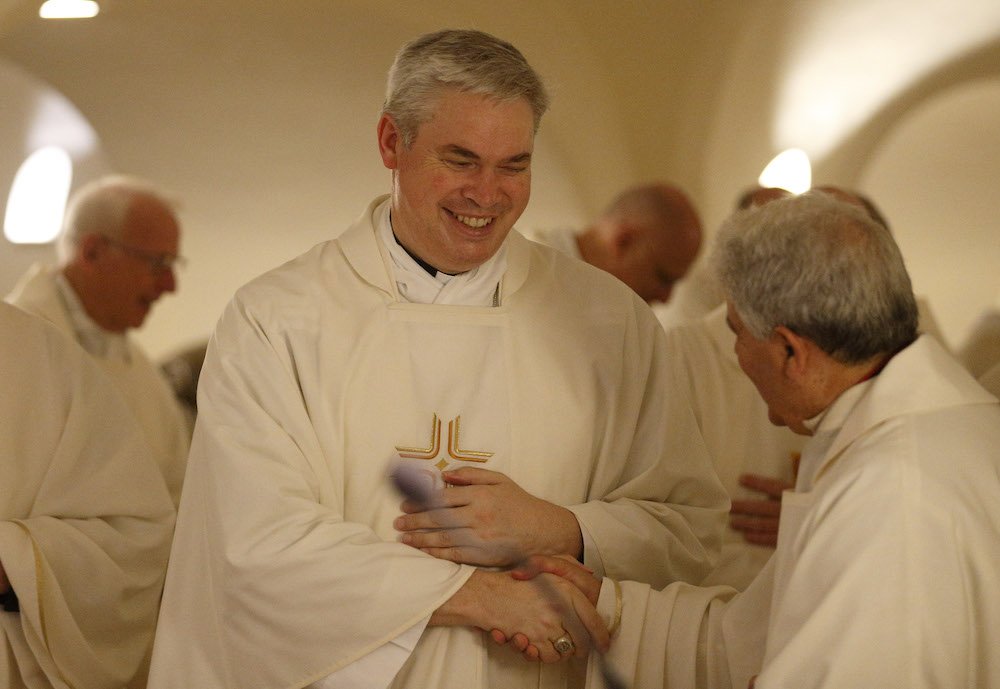 Auxiliary Bishop Richard Umbers of Sydney and other Australian bishops exchange the sign of peace as they concelebrate Mass in the crypt of St. Peter's Basilica at the Vatican June 24