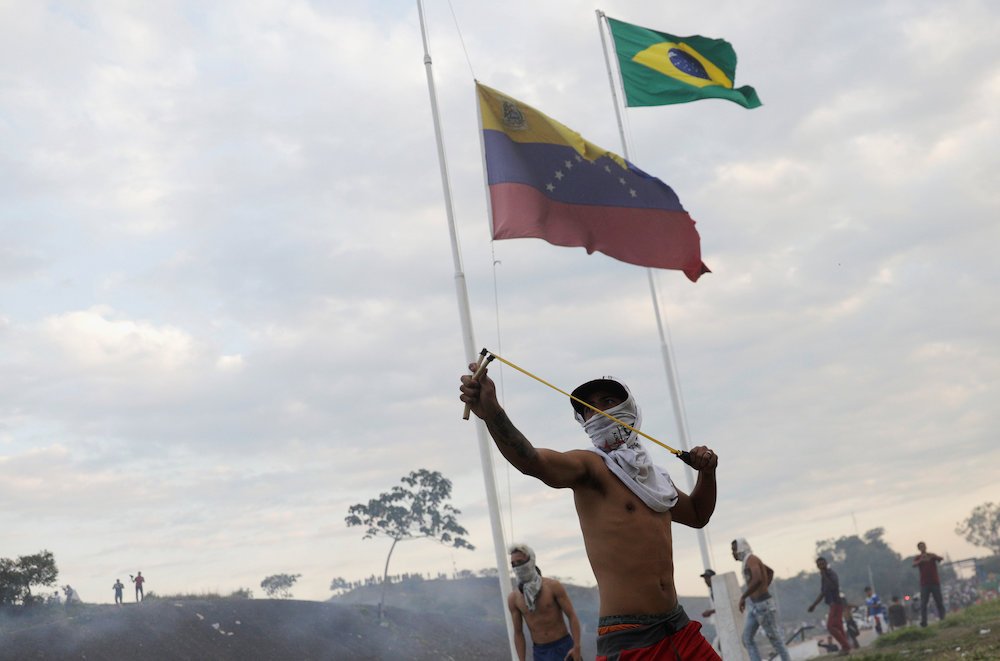 A protester uses a slingshot during clashes with security forces on the border between Venezuela and Brazil in Pacaraima