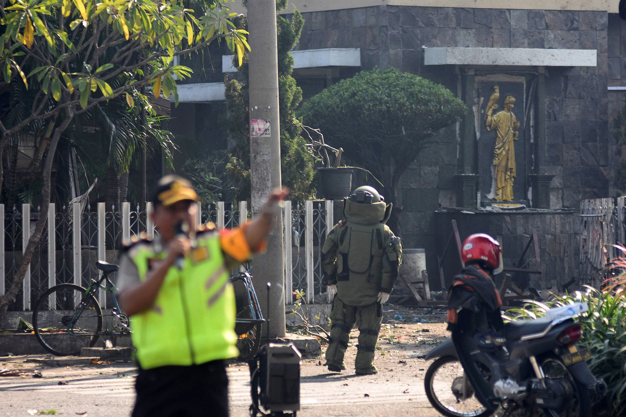 A member of the police bomb squad unit examines the site of a May 12 explosion outside Santa Maria Catholic Church in Surabaya