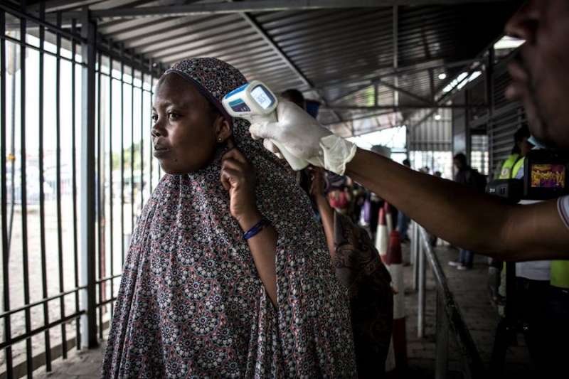 A woman gets her temperature measured at an Ebola screening station as she enters DCR from Rwanda. Credit: John Wessels / AFP / Getty Images.