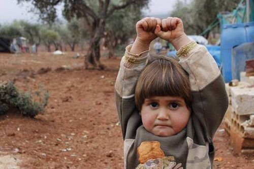 A young Syrian child raises her arms in a gesture of surrender. Credit: Osman Sagirli.