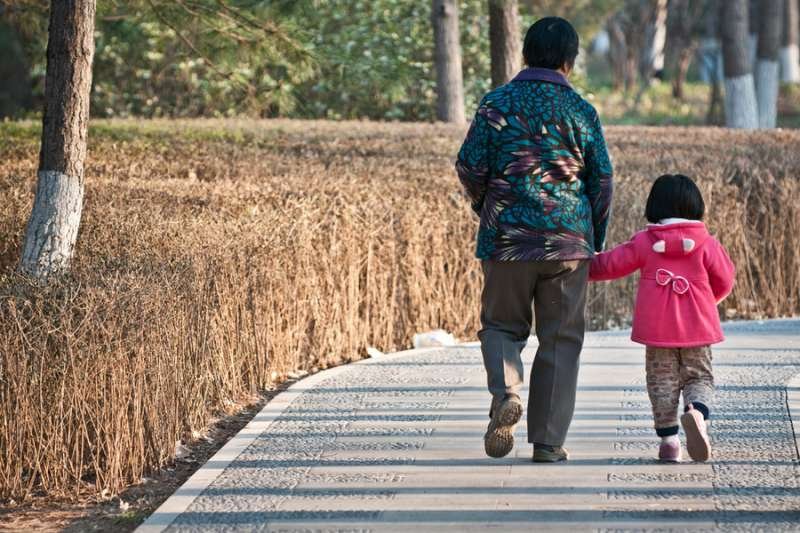 An old Chinese woman walks with her granddaughter. Credit: Fotokon/Shutterstock