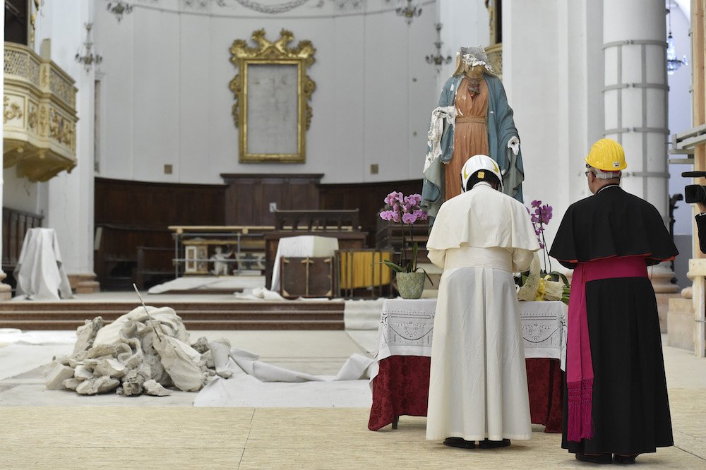 Pope Francis and Archbishop Francesco Massara of Camerino-San Severino Marche pray before a partially destroyed statue of Mary in the cathedral of Camerino