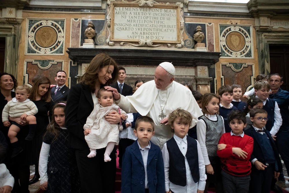Pope Francis greets a baby during an audience with members of the Italian charity